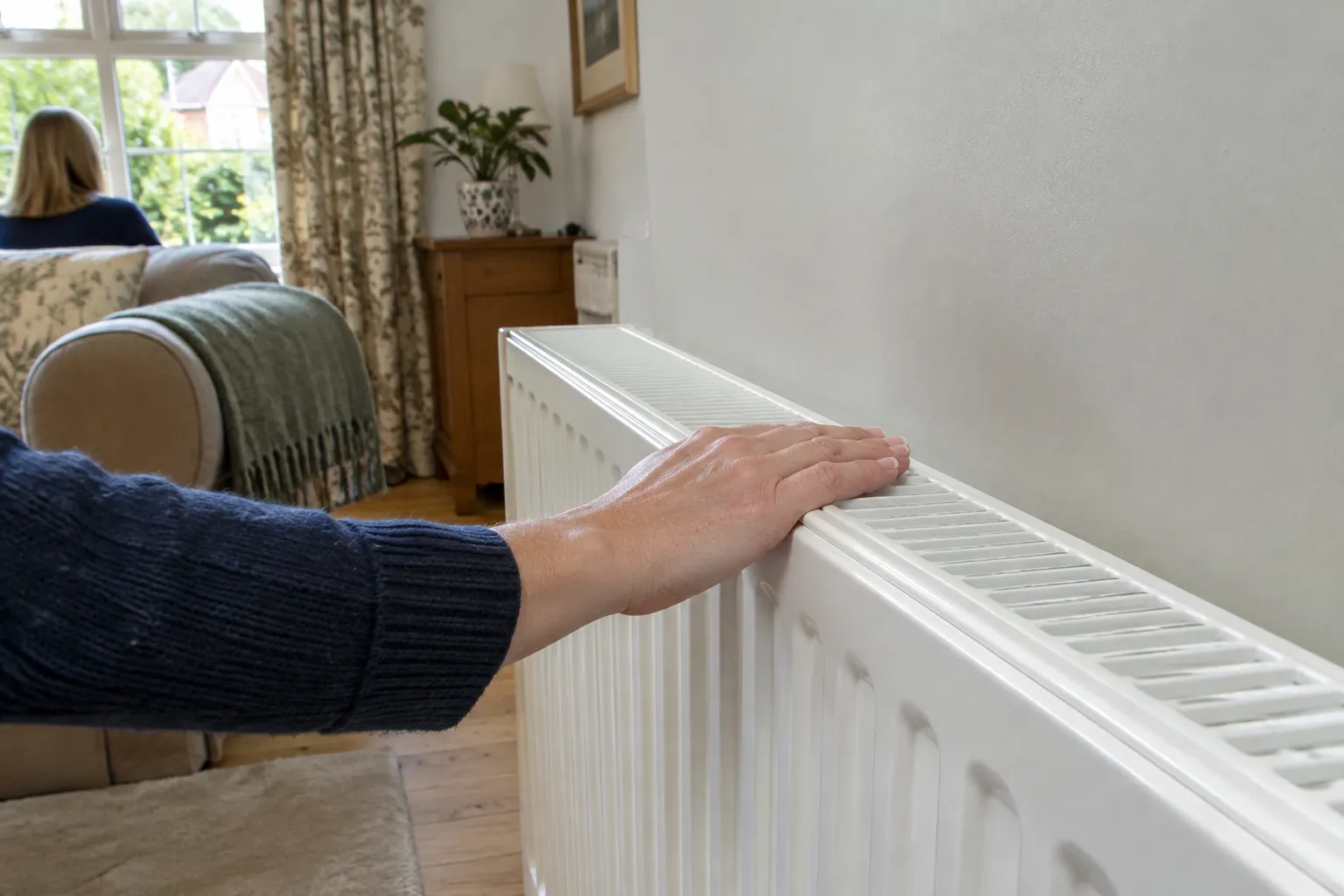 A hand checking the warmth of a radiator